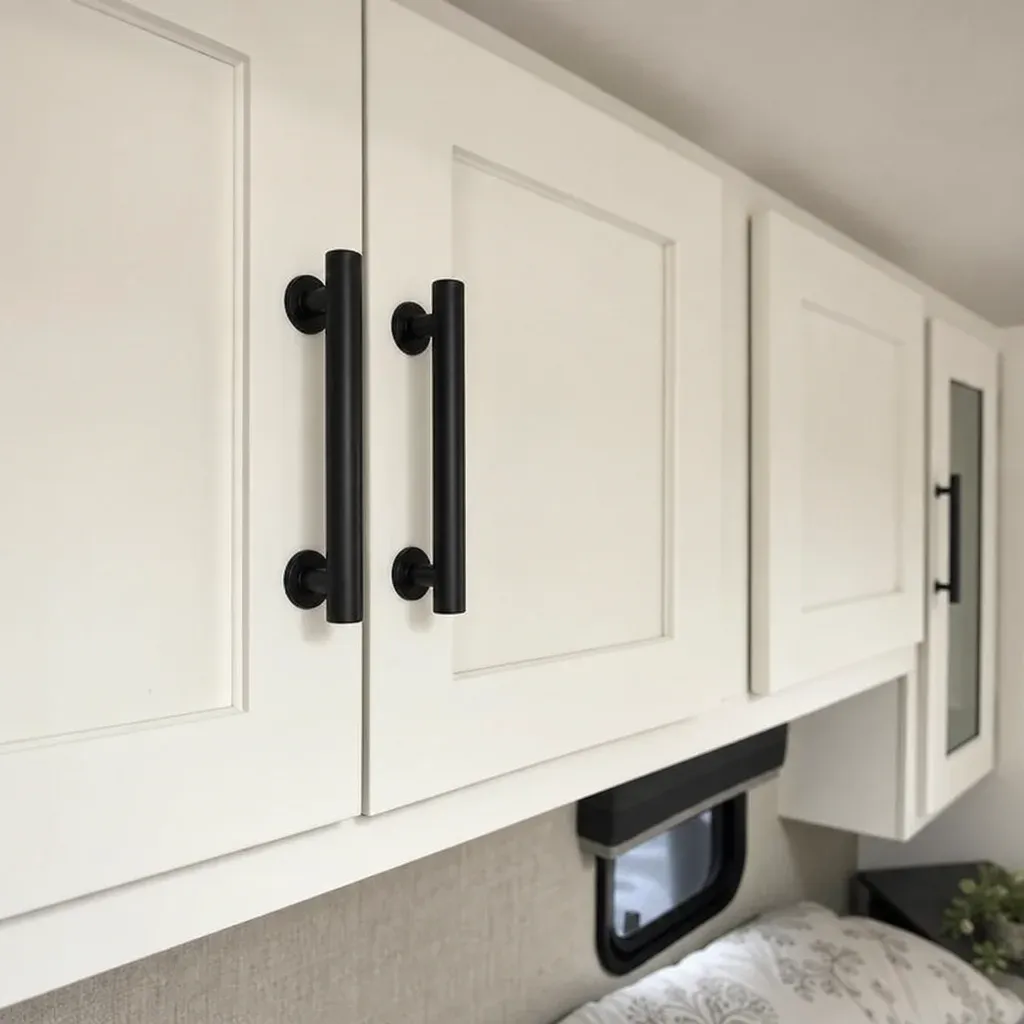 Close up of matte black farmhouse style hardware installed on freshly painted white RV bedroom cabinets