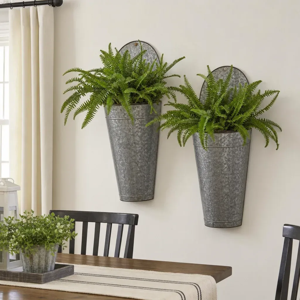 Galvanized metal wall planters filled with green ferns hanging on a white dining room wall