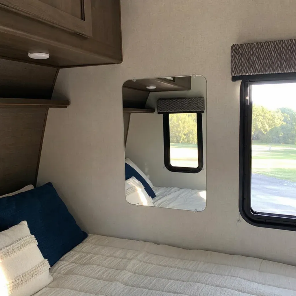 A strategically placed lightweight acrylic mirror in an RV bedroom reflecting the natural light from a window